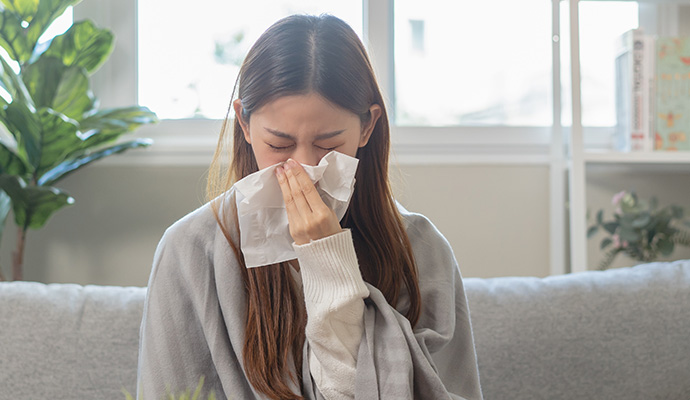 Person sneezing into a tissue